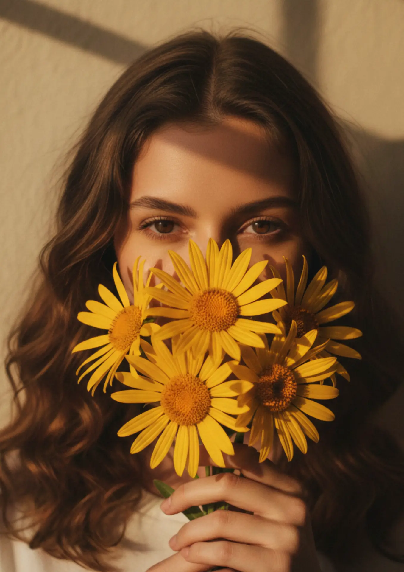 A woman holding a bunch of arnica flowers in warm golden light